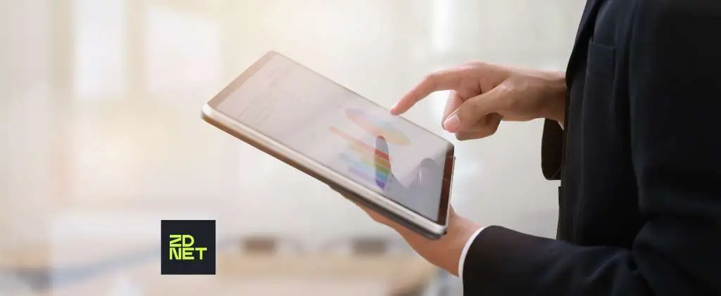 Personne en tenue professionnelle utilisant une tablette avec un graphique à l'écran ; Logo ZDNet visible dans le coin inférieur gauche, explorant les solutions en mode SaaS.