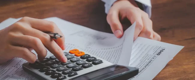 Une personne utilise une calculatrice pour les calculs CSPE.