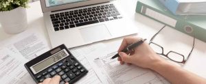 Une personne est assise à un bureau, utilisant une calculatrice pour calculer l'exonération CSPE.
