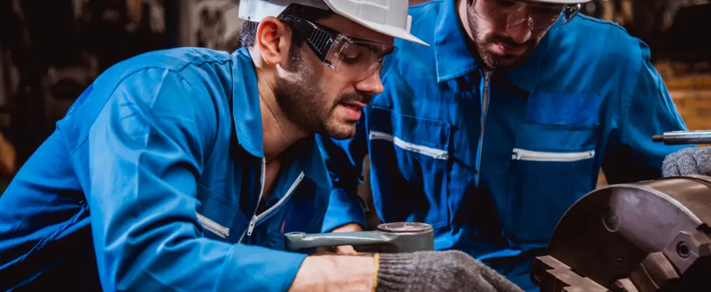 Deux ouvriers en uniforme bleu et équipement de sécurité opèrent efficacement des machines, conscients de la nécessité de l'efficacité énergétique industrie.