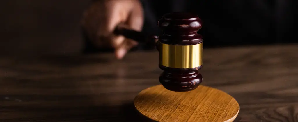 Un marteau frappe un bloc sonore en bois, résonnant avec l'autorité décisive d'un jugement juridique, à l'image des considérations imminentes du projet de loi de finances 2025.