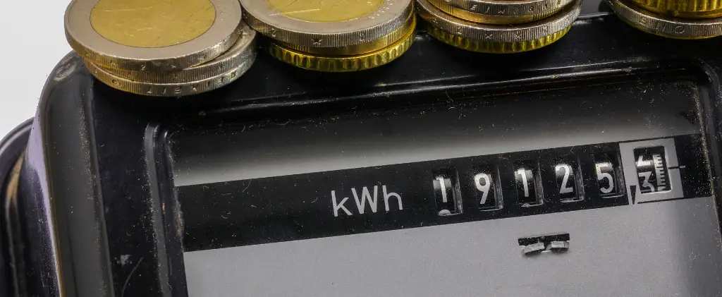 Un compteur électrique analogique, étiqueté énergie pro, affiche 19125 kWh avec plusieurs pièces empilées perchées dessus.