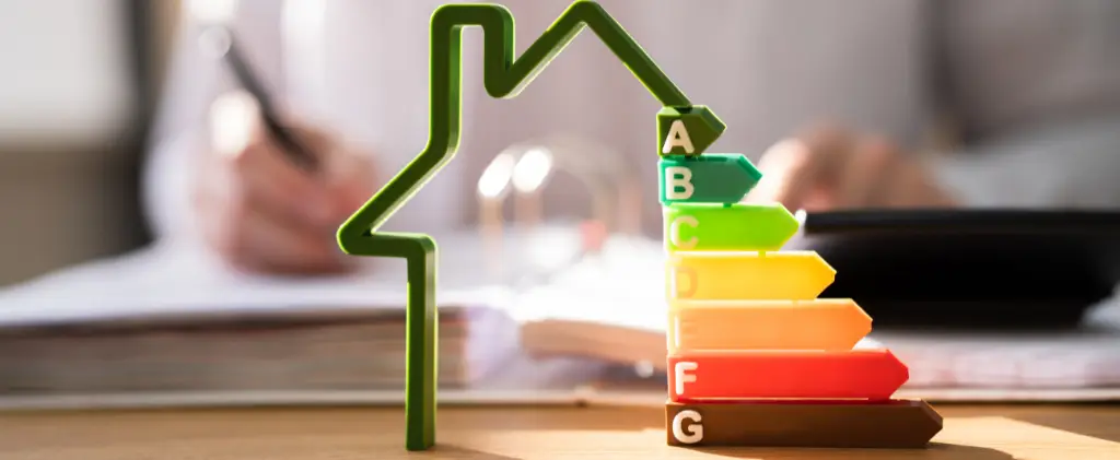 Une silhouette de maison verte se dresse à côté d'un ensemble de flèches multicolores indiquant l'efficacité énergétique, étiquetées de A à G. En arrière-plan, une personne d'un fournisseur d'énergie pro travaille avec diligence à son bureau.