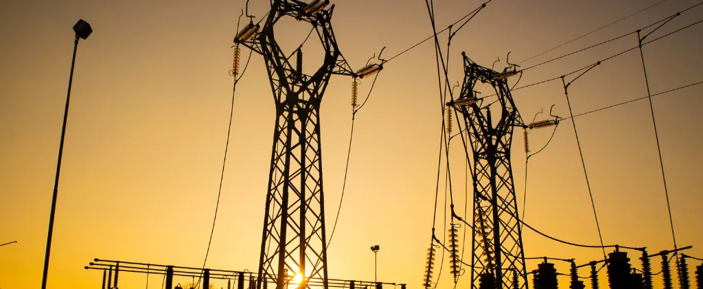 Les silhouettes des pylônes électriques et des lignes électriques s'étendent dans le ciel du coucher du soleil, incarnant l'infrastructure énergétique essentielle.
