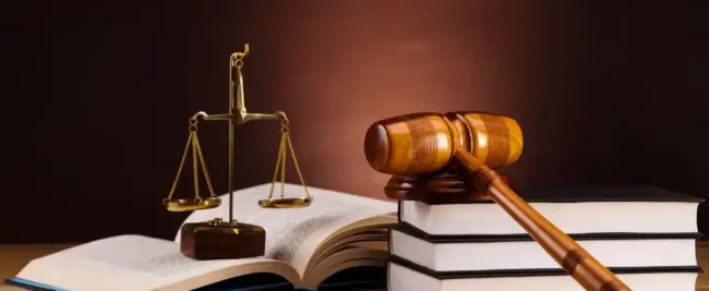 Un marteau repose sur des livres empilés à côté d'une balance sur un fond sombre, symbolisant la baisse de 15 % de la jurisprudence TRVE.