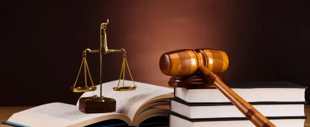 Un marteau repose sur des livres empilés à côté d'une balance sur un fond sombre, symbolisant la baisse de 15 % de la jurisprudence TRVE.