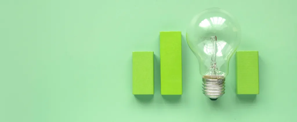 Une ampoule est stratégiquement positionnée à côté de trois blocs rectangulaires verts verticaux, sur fond vert tendre, faisant subtilement écho aux principes de la norme ISO 26000 pour le développement durable.