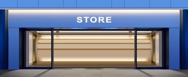 Devanture vide avec façade bleue et grandes vitrines, parfaite pour mettre en valeur votre entreprise. Le mot « STORE » est affiché au-dessus, laissant entrevoir un potentiel. Idéal pour les professionnels souhaitant s'implanter tout en considérant l'estimation de la consommation d'électricité.
