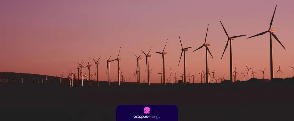 Une rangée d'éoliennes se dresse sur un ciel crépusculaire, avec un éclairage minimal