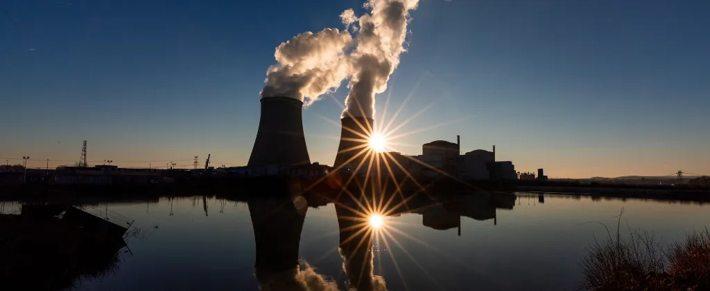 Une personne en pull jaune travaille sur un ordinateur portable posé sur une table en bois.