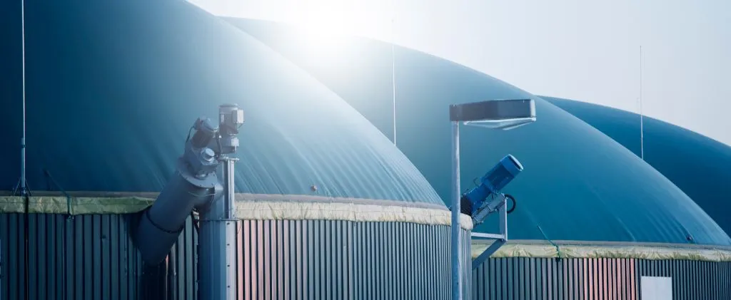 Grands dômes industriels avec tuyaux et équipements sous un ciel clair, faisant partie d'une installation de gestion de biogaz