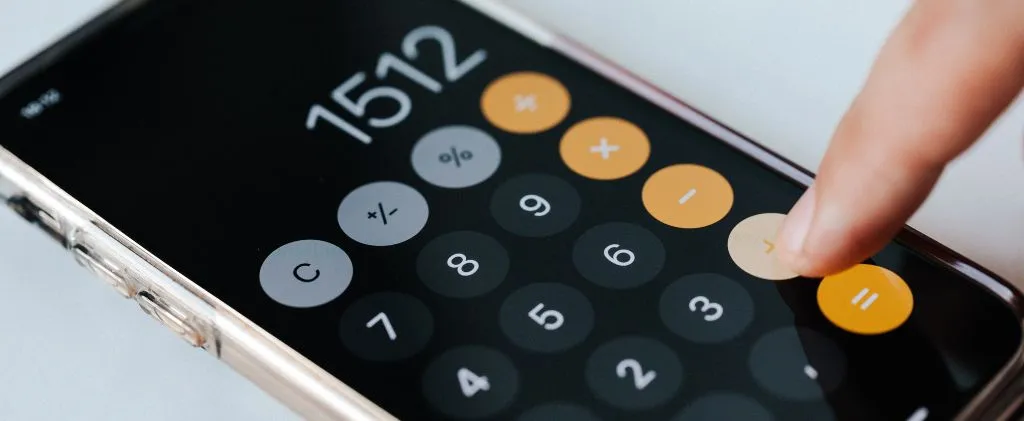 Gros plan d'un smartphone affichant une application de calculatrice avec le numéro 1512, tandis qu'un doigt appuie sur le bouton égal, parfait pour des calculs rapides de kva et de kW en déplacement.