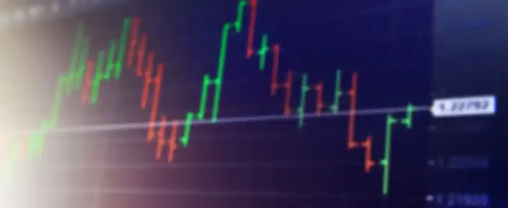 Image floue d'un graphique financier affichant des chandeliers rouges et verts sur un fond sombre, indiquant les fluctuations des prix du marché et reflétant l'énergie derrière un achat dynamique.