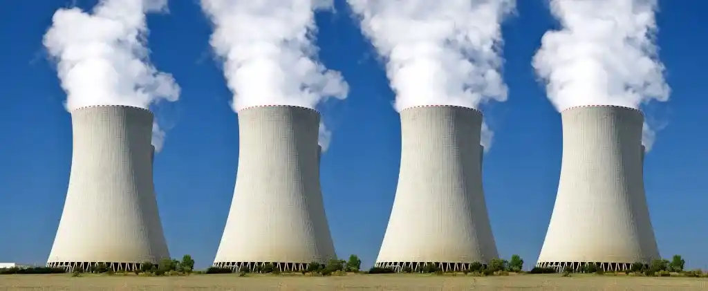 Quatre grandes tours de refroidissement d'une centrale électrique émettent de la vapeur blanche sur fond de ciel bleu, mettant en évidence l'optimisation des puissances de raccordement, avec de l'herbe verte au premier plan.