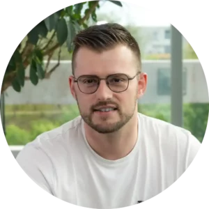 Un homme aux cheveux bruns courts, à la barbe et aux lunettes, portant un t-shirt blanc, est assis à l'intérieur, entouré de verdure et de grandes fenêtres - une scène calme qui suggère un nouveau mécanisme de capacité pour l'inspiration.